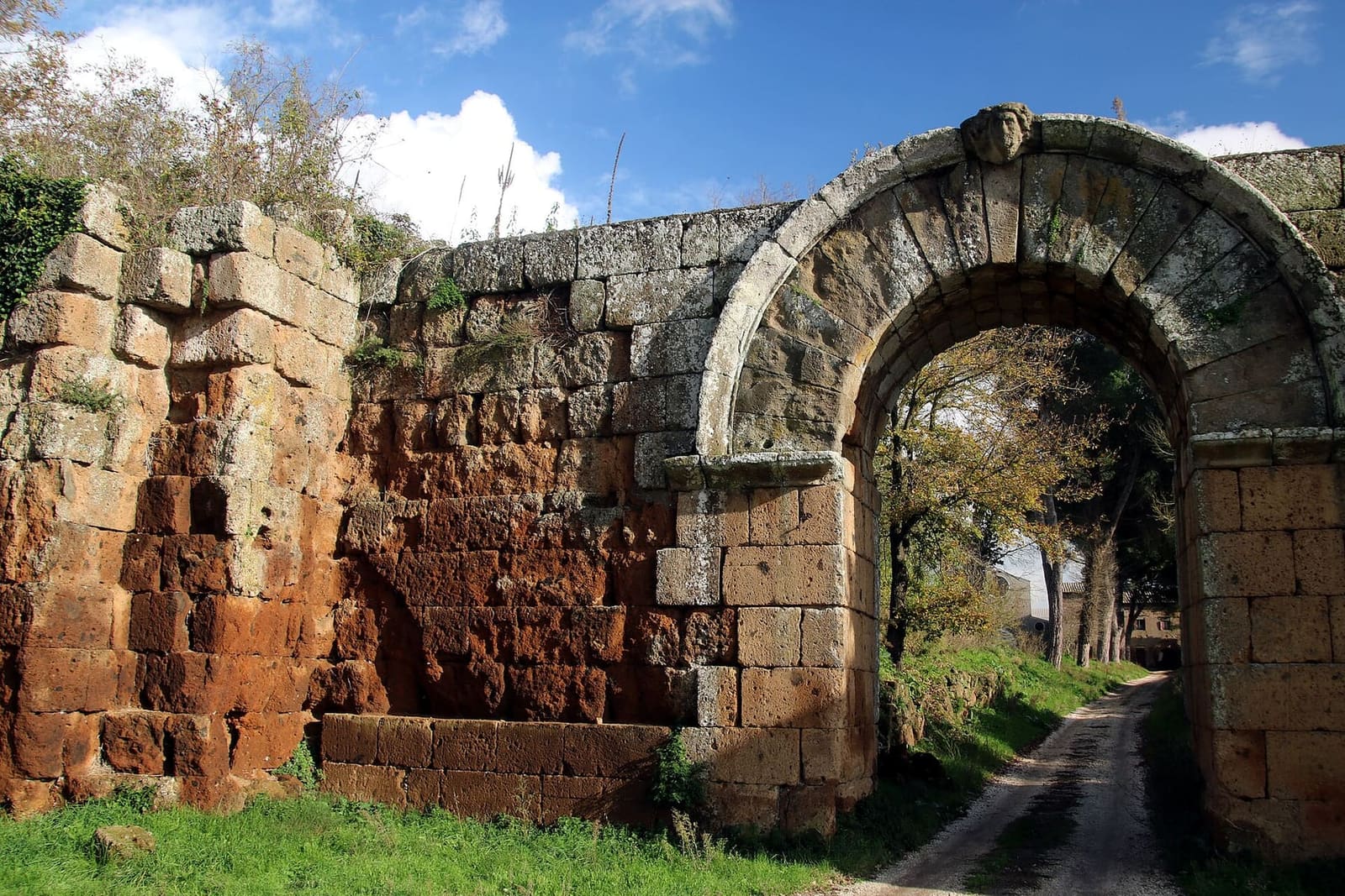 la Porta di Giove di sbieco, con accanto la cortina di tufo rosso e i blocchi di una torre che sporgono dal filo delle mura