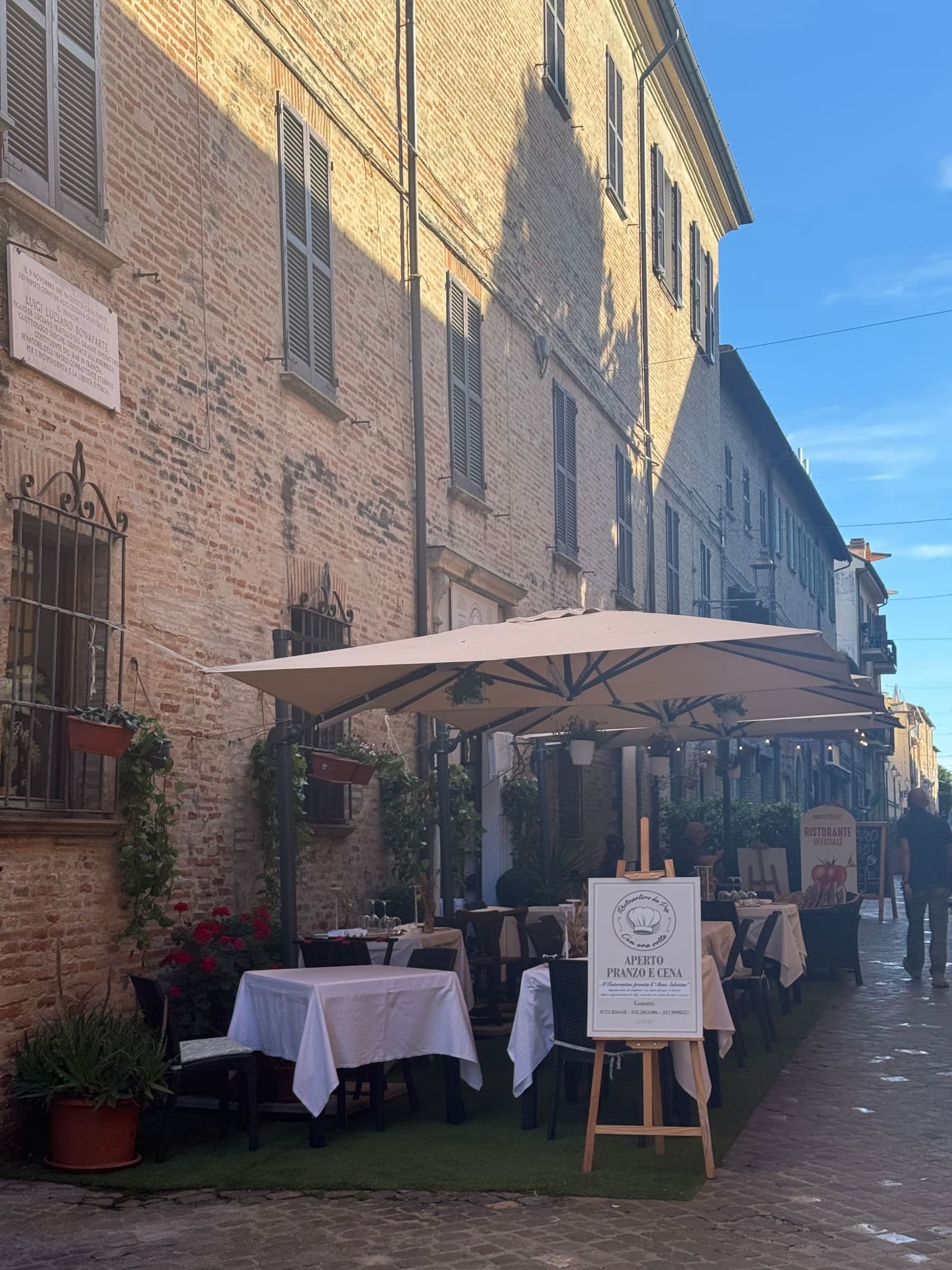 i tavolini apparecchiati sotto l'ombrellone in un vicolo del centro