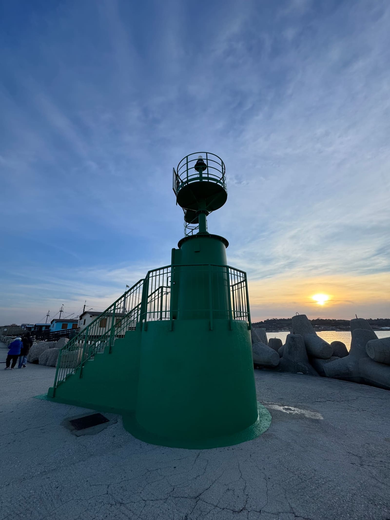 il fanale verde in fondo al molo, con il sole che scende dietro