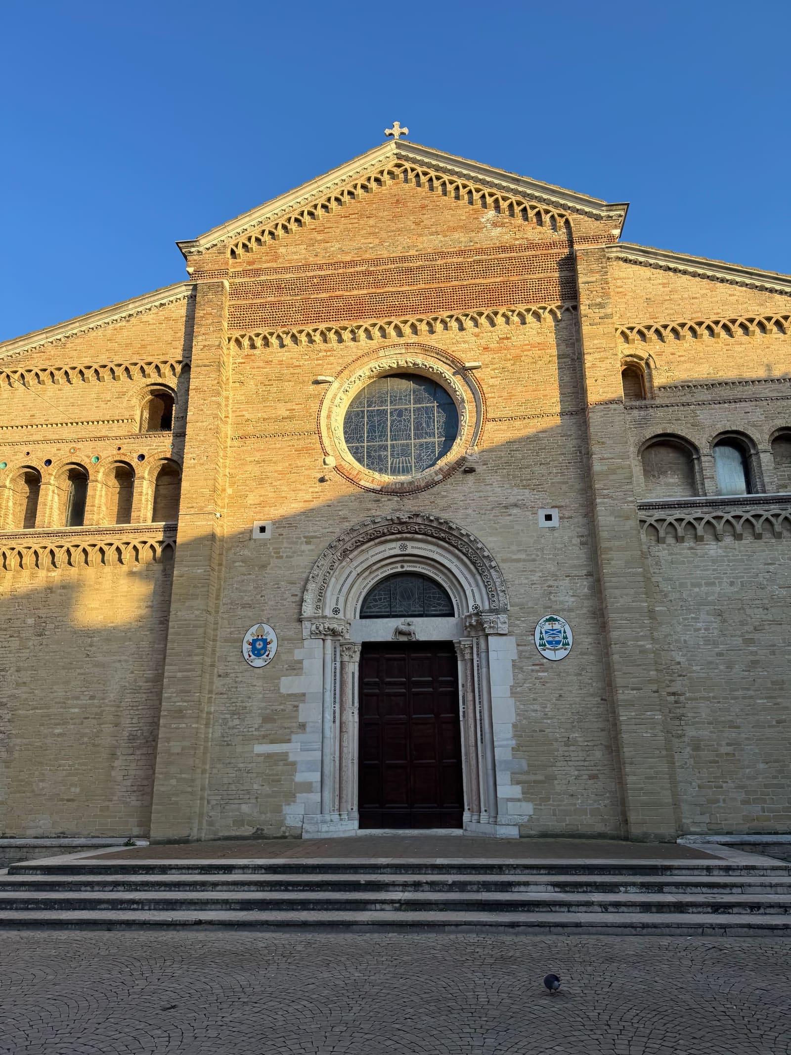 la facciata in laterizio della cattedrale con il rosone, su piazza Clemente VIII