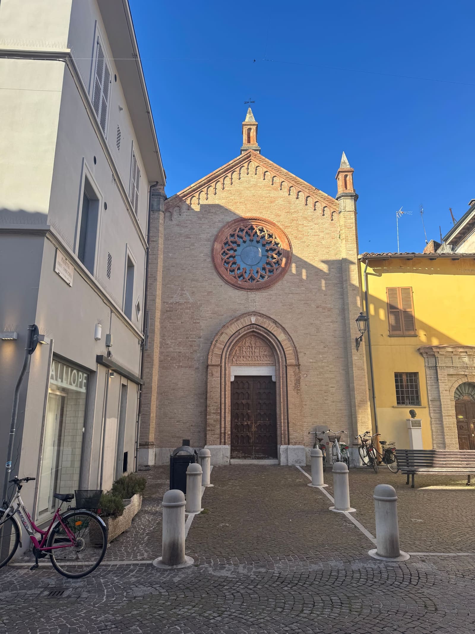 la chiesa di San Tommaso in fondo alla via, con il rosone e i mattoni a vista