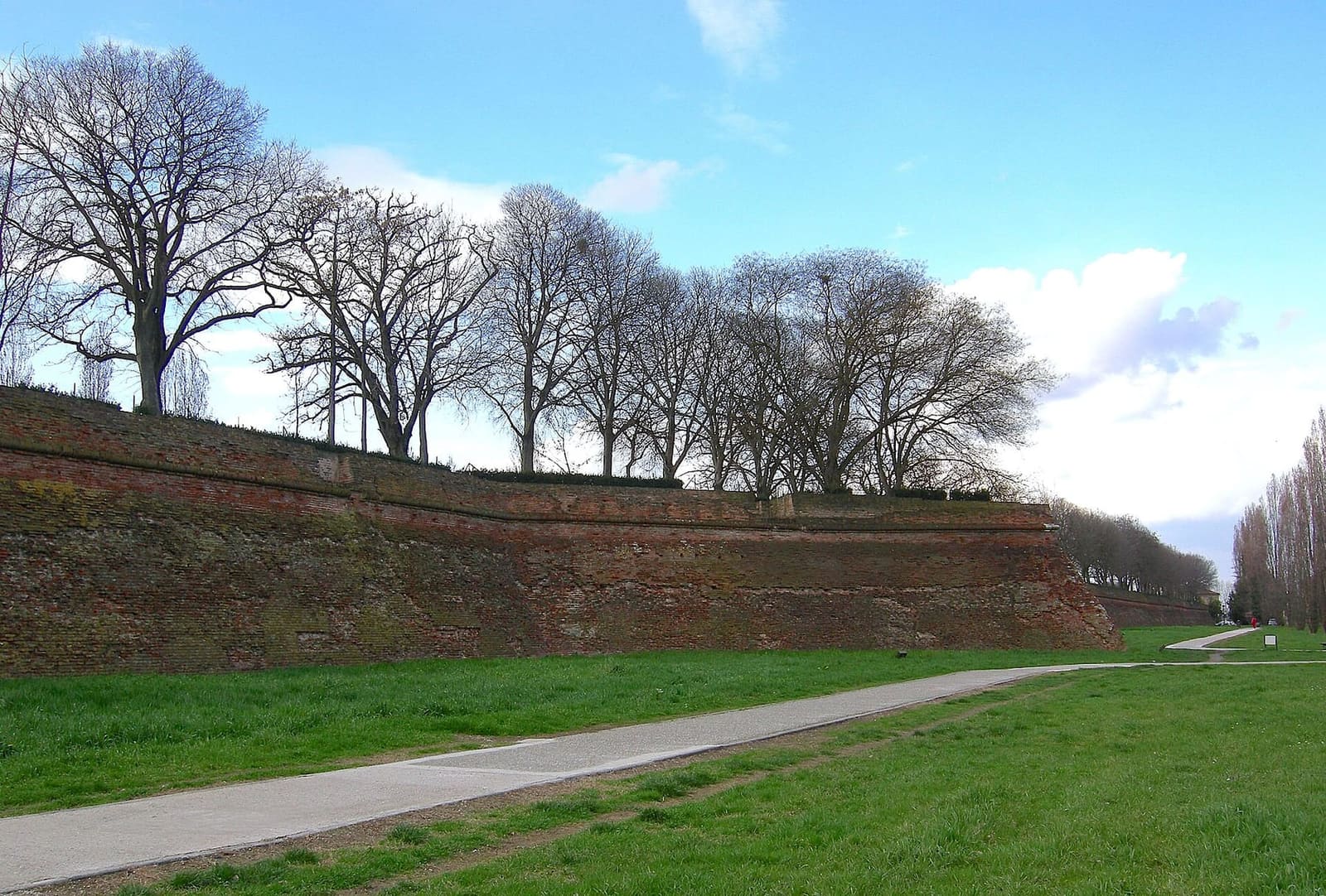 die Stadtmauer von Ferrara nahe der Porta San Giovanni, mit dem Pfad im Graben und den kahlen Bäumen