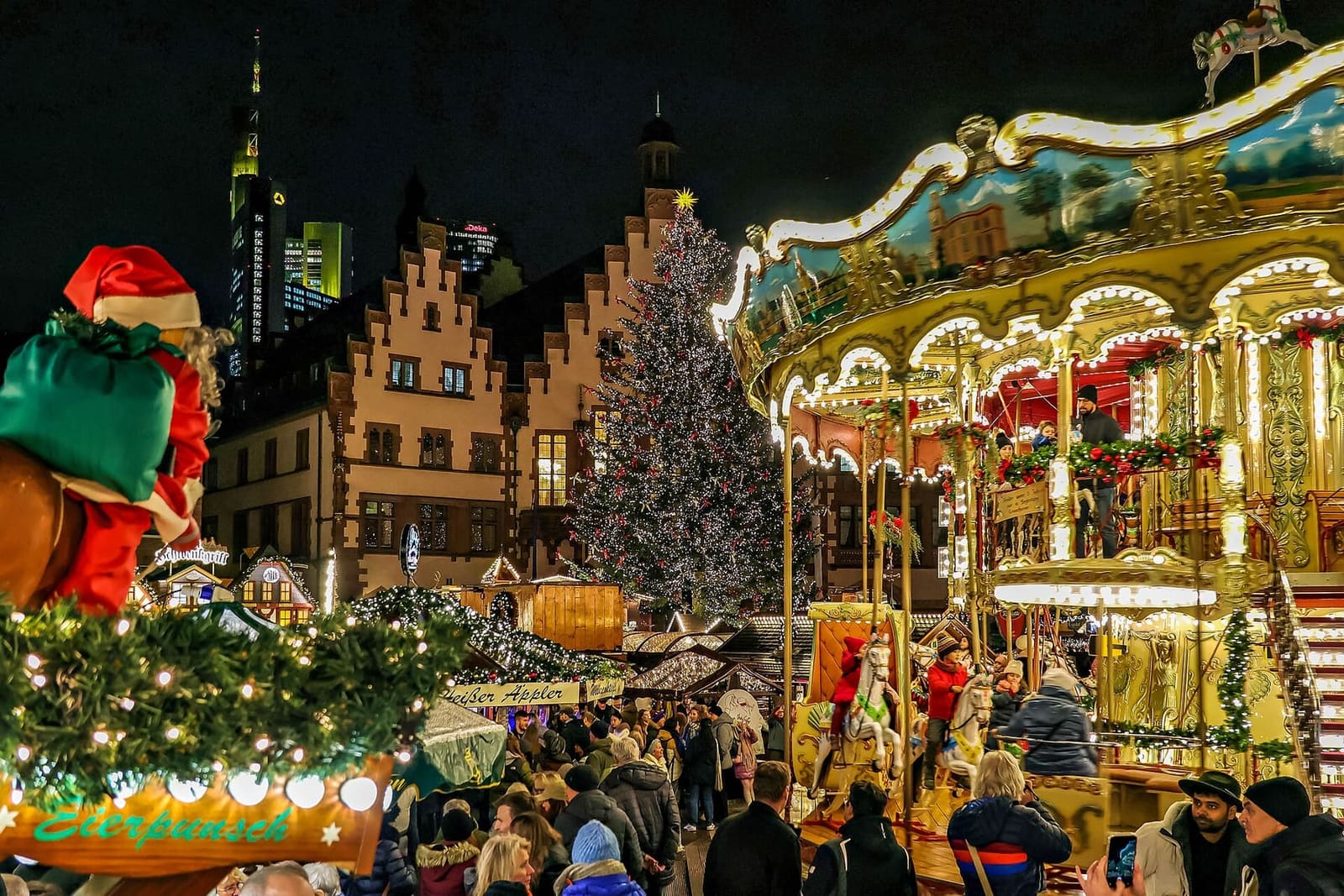 la giostra a due piani del mercatino sul Römerberg, con il Römer e l'albero illuminato dietro