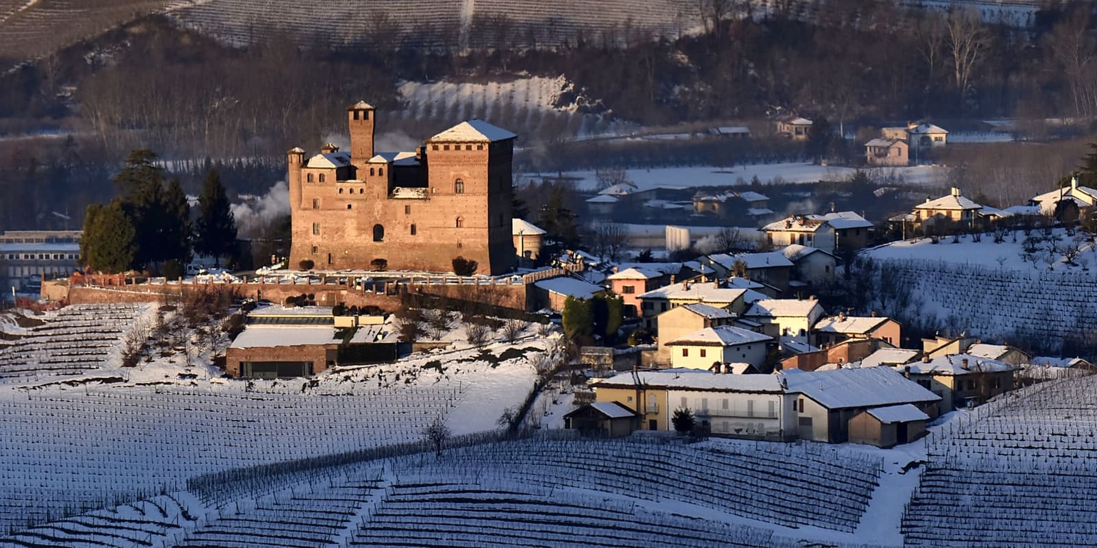 il castello e le case del borgo con la neve, alla prima luce del mattino