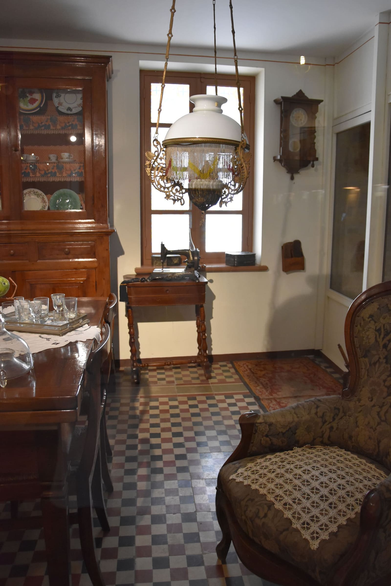 una delle stanze arredate del museo, con la credenza, la lampada a sospensione e la poltrona