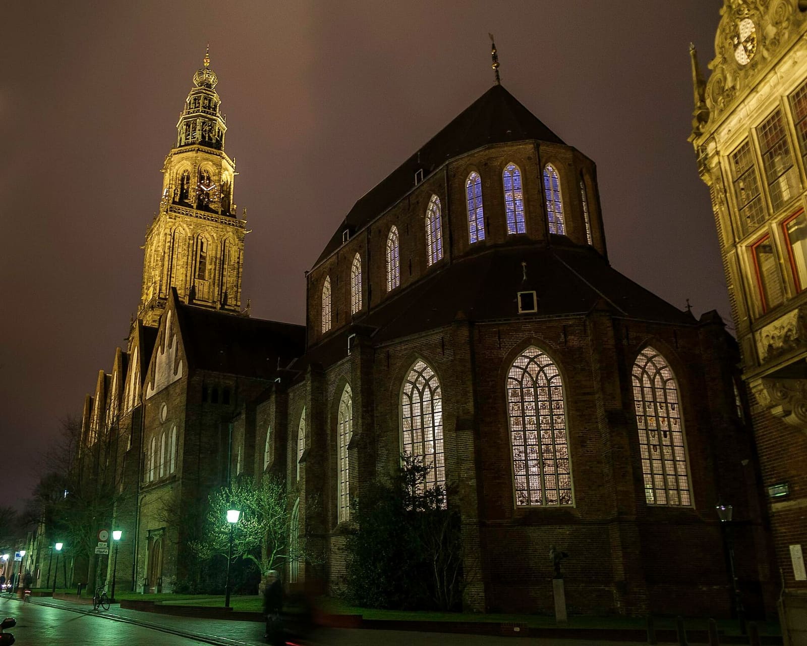 la Martinikerk di sera, con le vetrate accese e la Martinitoren illuminata