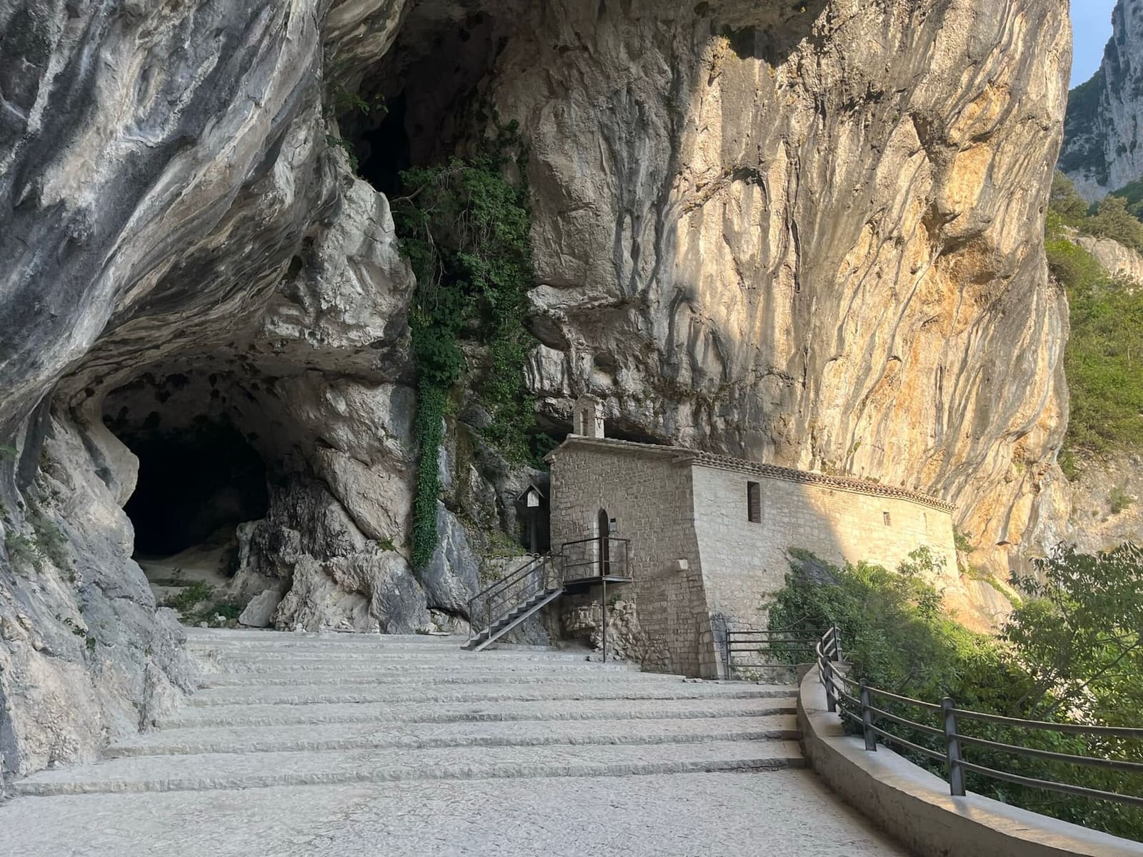 l'eremo di Santa Maria infra Saxa, costruito in pietra sotto la parete, con la scalinata e l'ingresso della grotta accanto