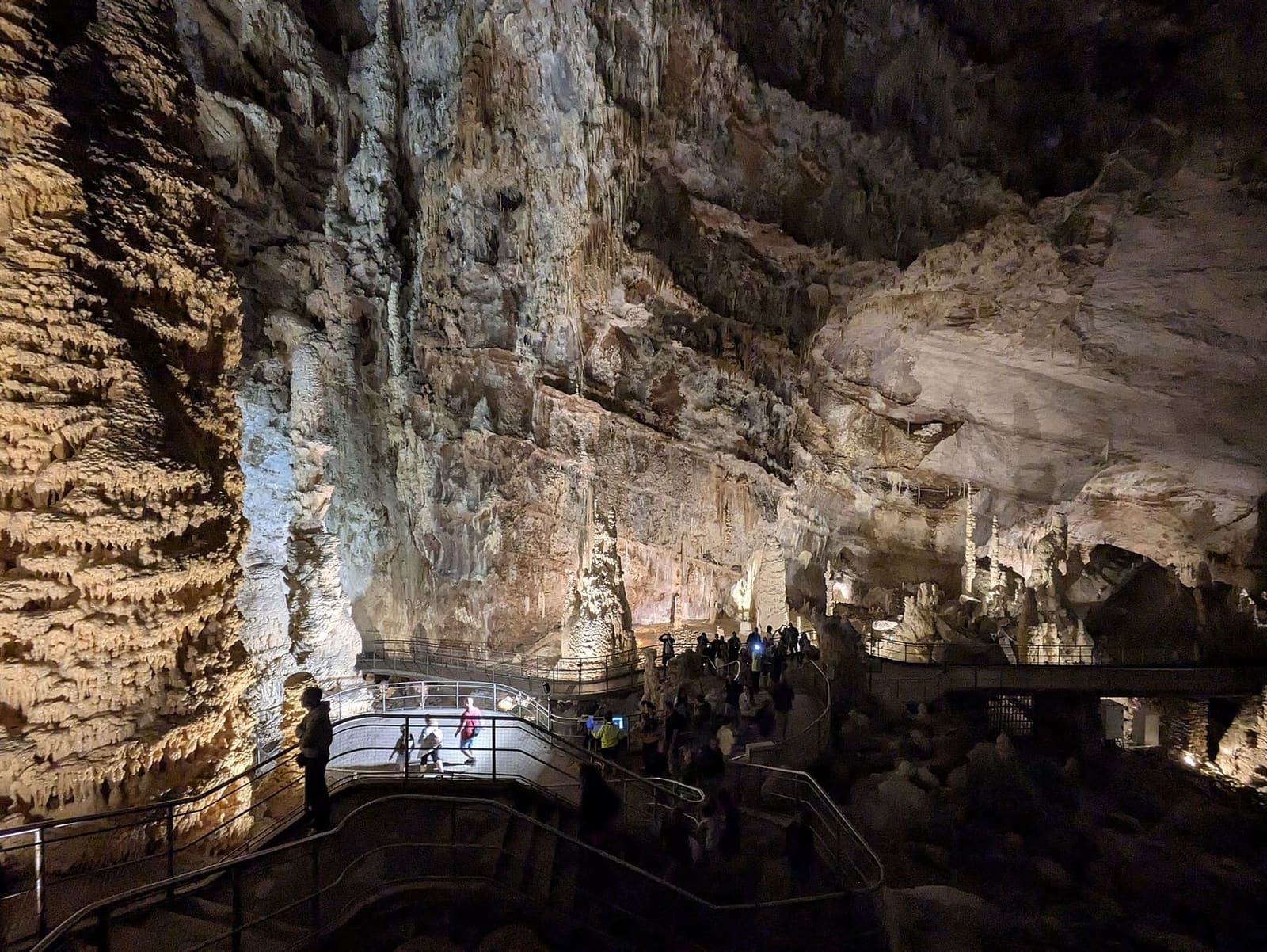 una sala così grande che le persone sulla passerella, in basso, sono puntini contro la parete di calcite