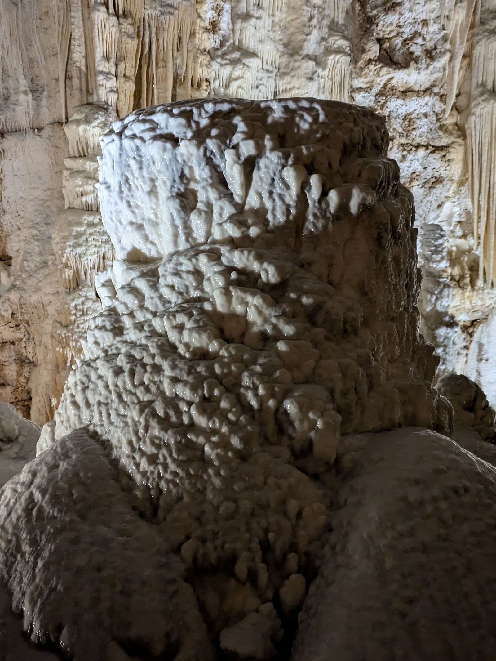 una stalagmite massiccia e tronca in cima, coperta di bolle di calcite come una scorza