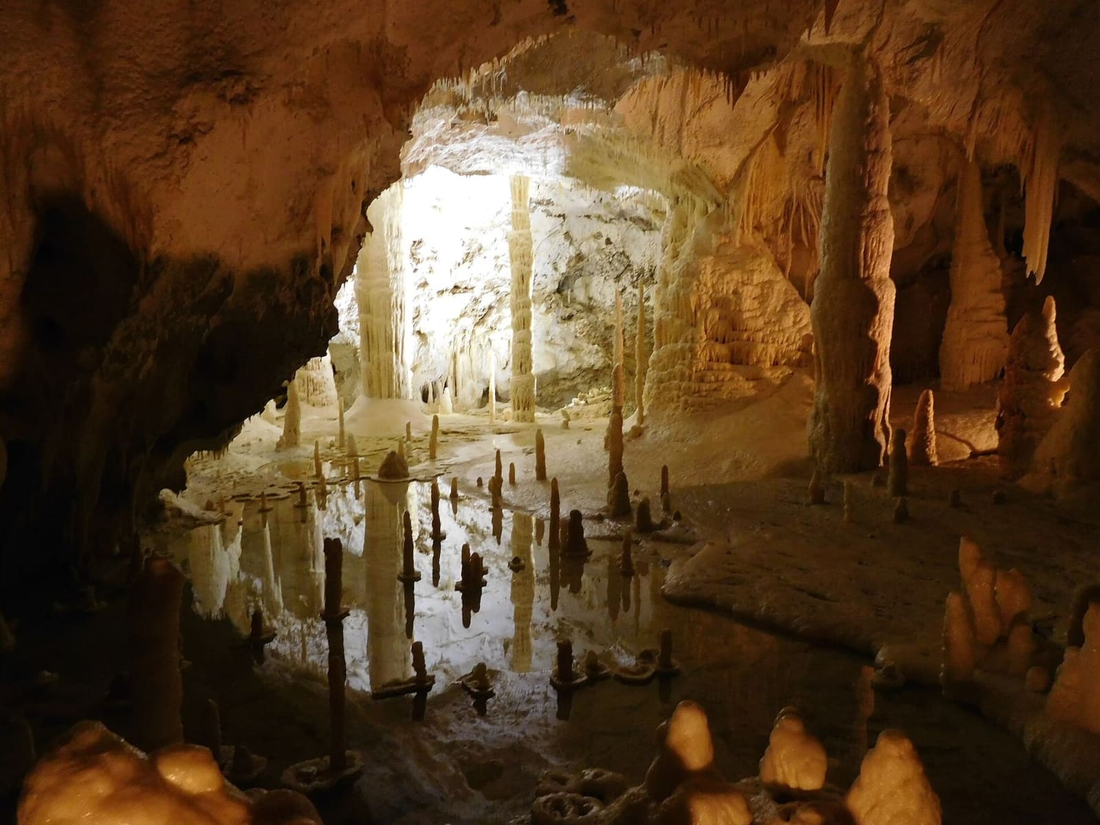 le stalagmiti basse che si specchiano nell'acqua ferma, con la luce calda dietro le colonne