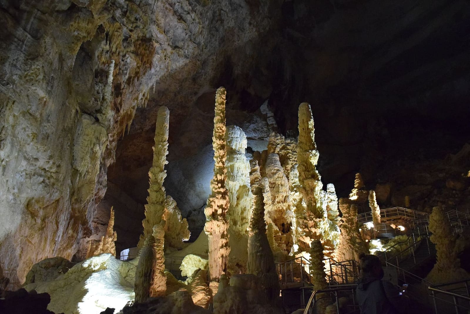 un gruppo di stalagmiti alte come torri, tutte bianche, illuminate dal basso contro la volta scura