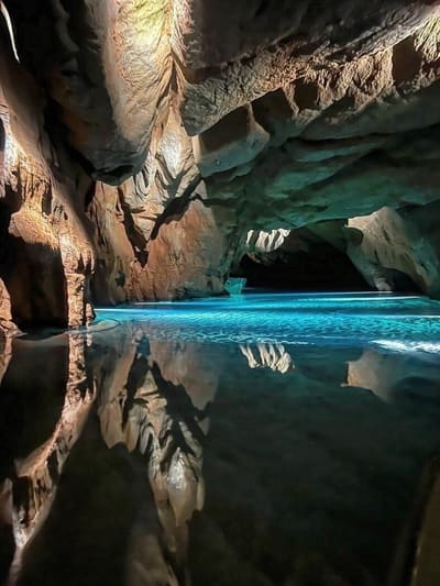 la roccia riflessa nell'acqua ferma, con una barca in fondo alla galleria