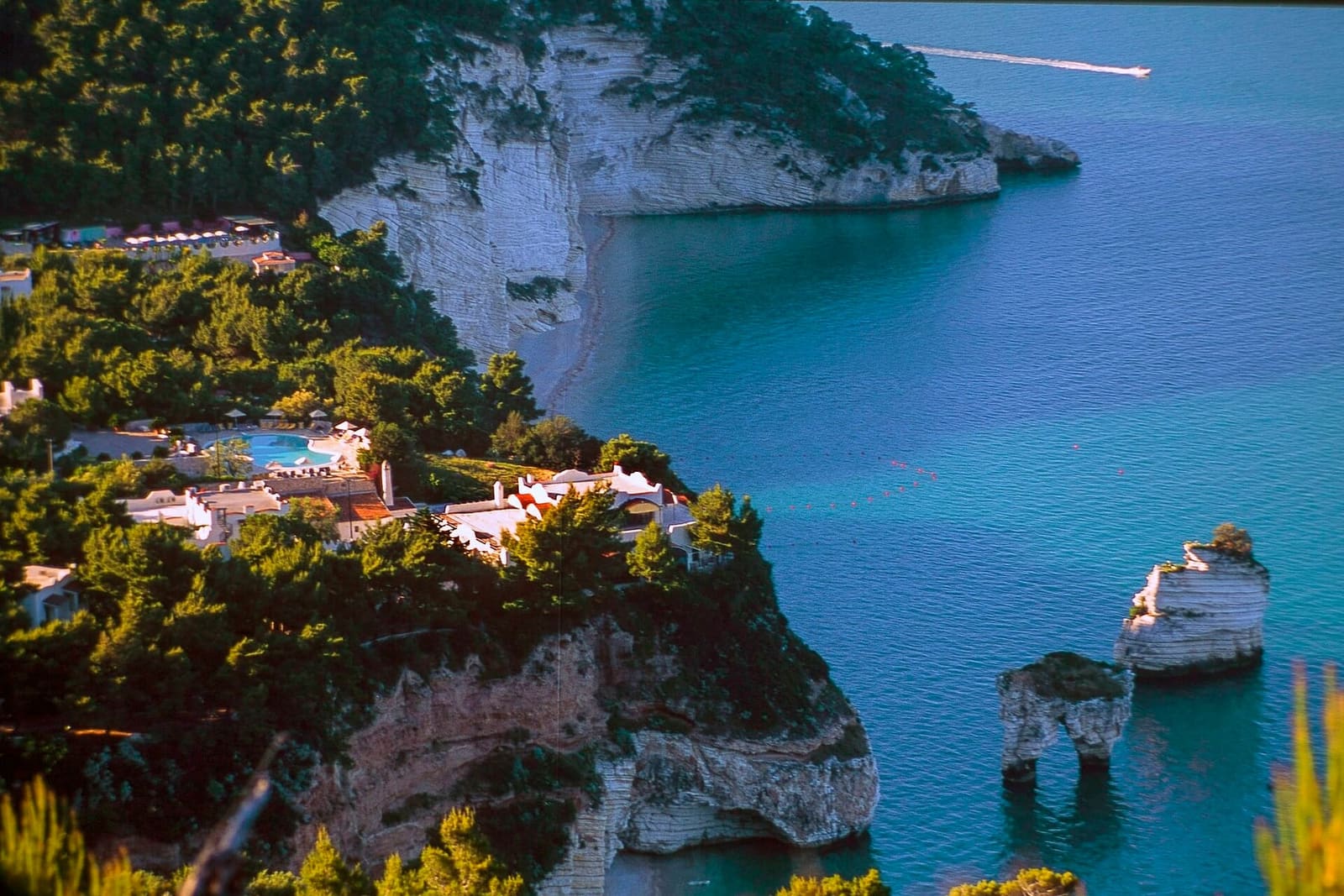 la baia con l'albergo sulla scogliera e i faraglioni in basso