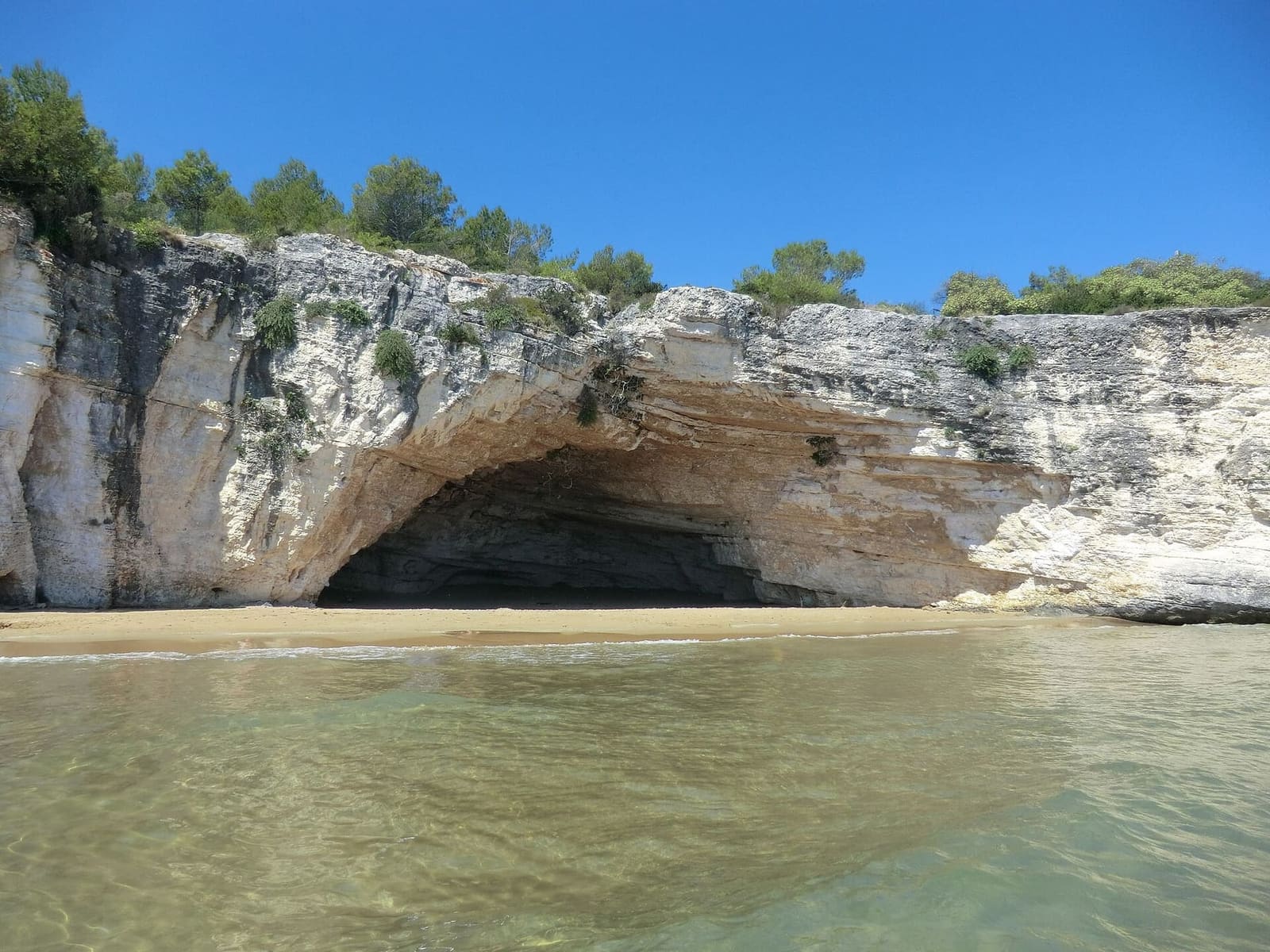 la spiaggia e la Grotta dei Colombi, scavata nella falesia bianca, sulla costa di Vieste