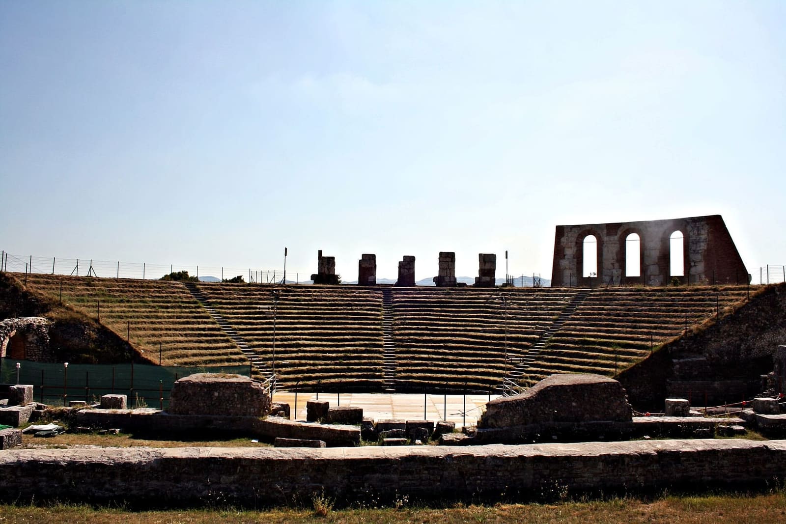 la cavea del teatro romano vista dalla scena, con le gradinate e in alto i resti delle arcate