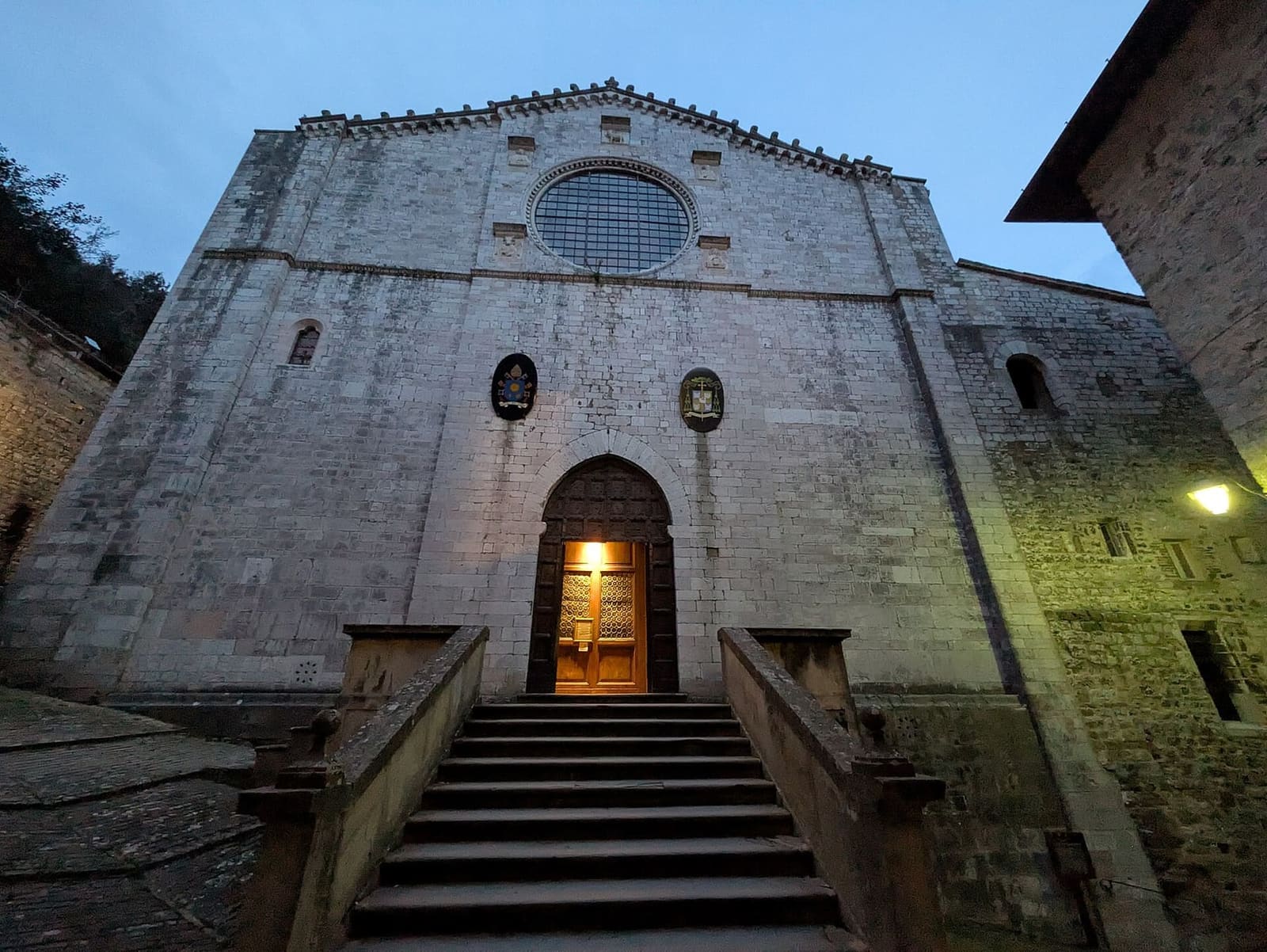 la facciata della cattedrale dei Santi Mariano e Giacomo la sera, con il rosone, la scalinata e il portale acceso