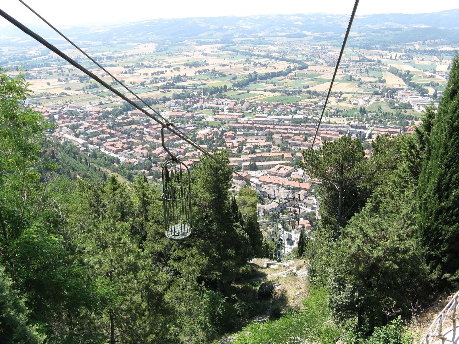 le gabbie della funivia che scendono lungo il fianco del monte, con Gubbio e la pianura sotto