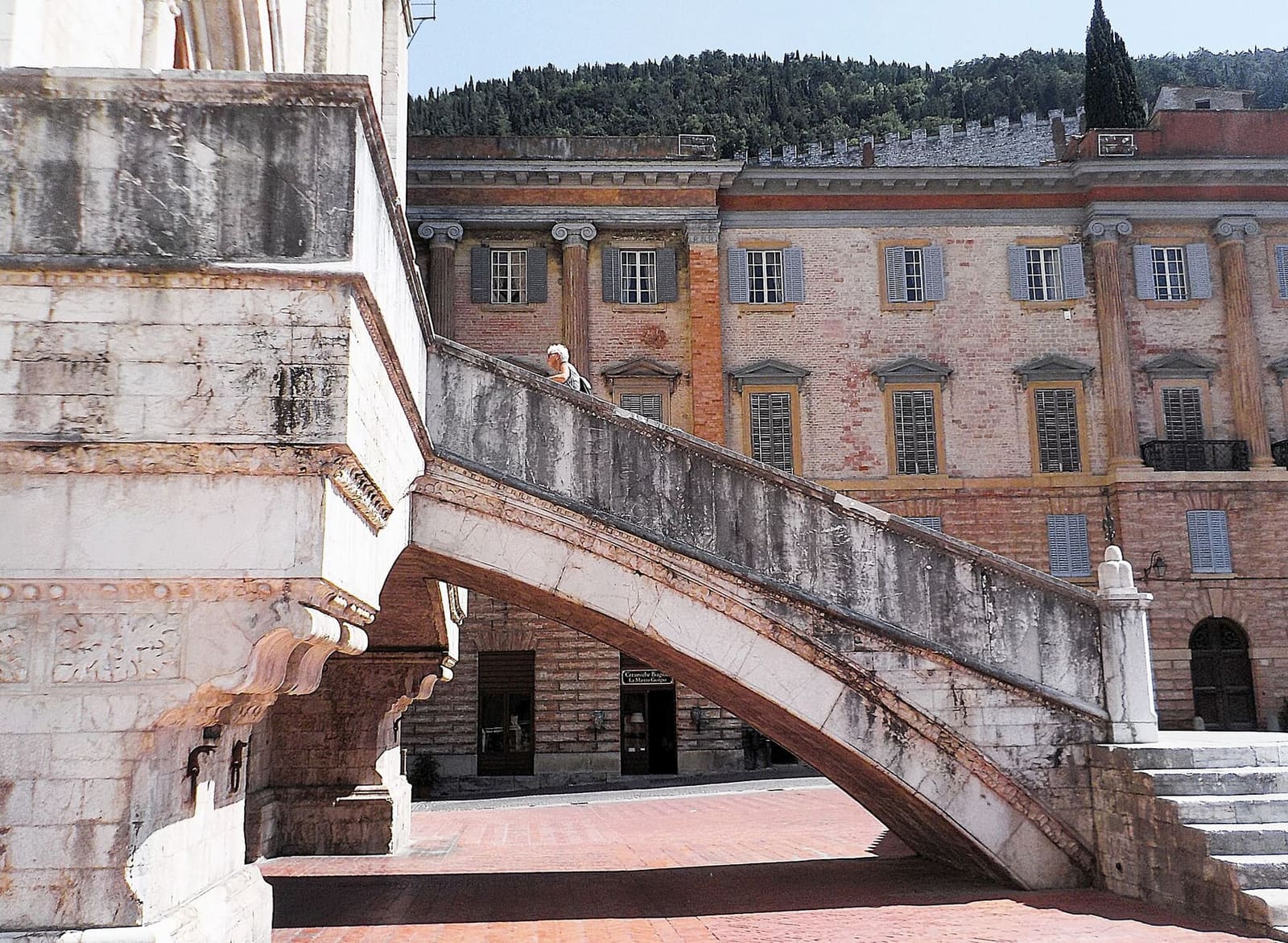 la scalinata a ventaglio del Palazzo dei Consoli che scende in piazza sopra un arco, con il Palazzo Ranghiasci di fronte
