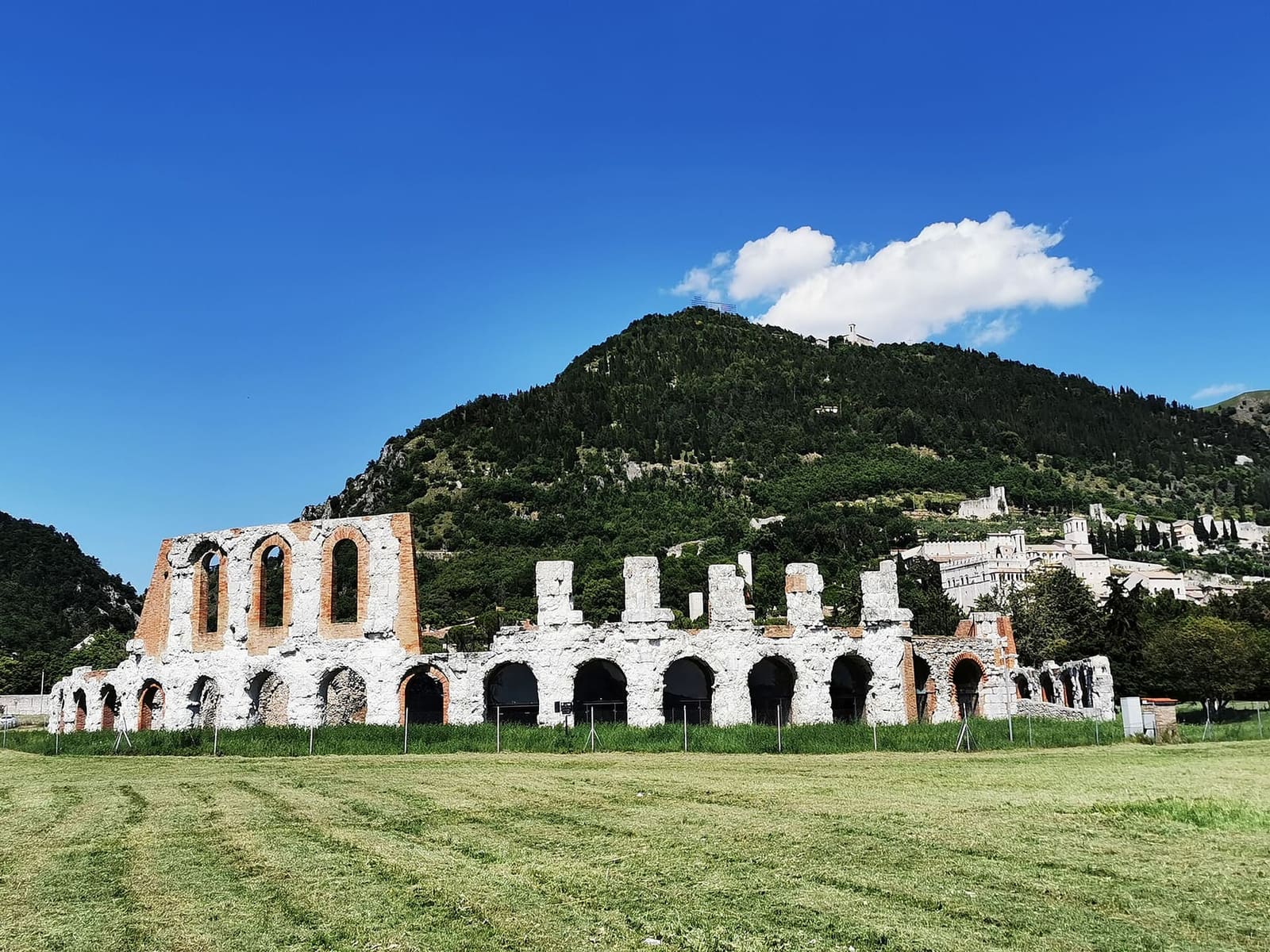 il giro esterno del teatro romano, due ordini di arcate di pietra bianca, sotto il monte Ingino