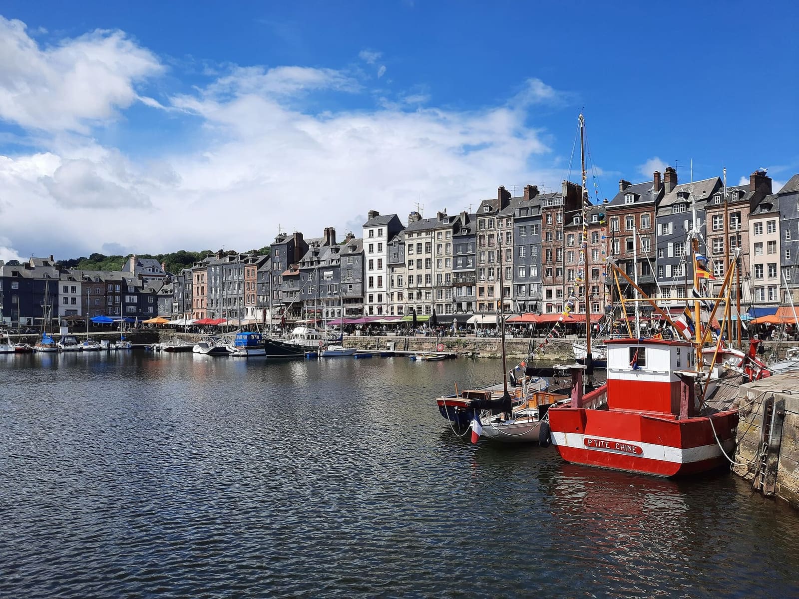 il Vieux Bassin con le case alte del quai Sainte-Catherine e un peschereccio rosso all'ormeggio, a maggio