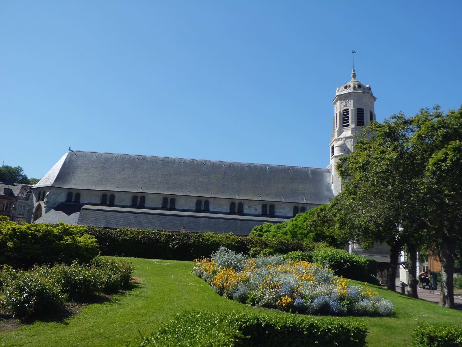 l'église Saint-Léonard con la navata lunga e il campanile, vista dal giardino fiorito, a maggio