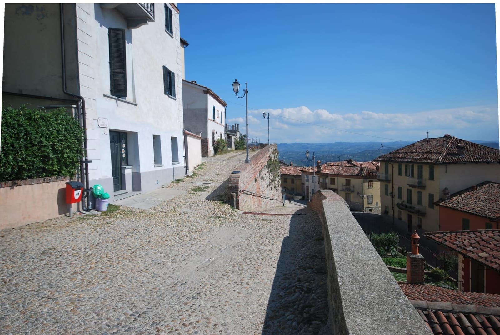 la salita di ciottoli lungo i bastioni, con i tetti del paese e le colline sullo sfondo