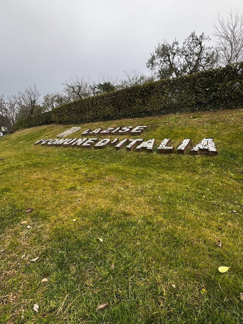 la scritta Lazise 1° Comune d'Italia composta con sassi bianchi sul prato all'ingresso del paese