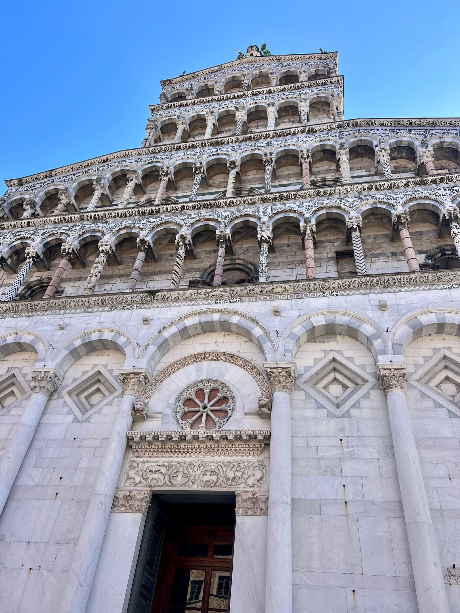 le file di logge sulla facciata di San Michele in Foro, con il rosone sopra il portale