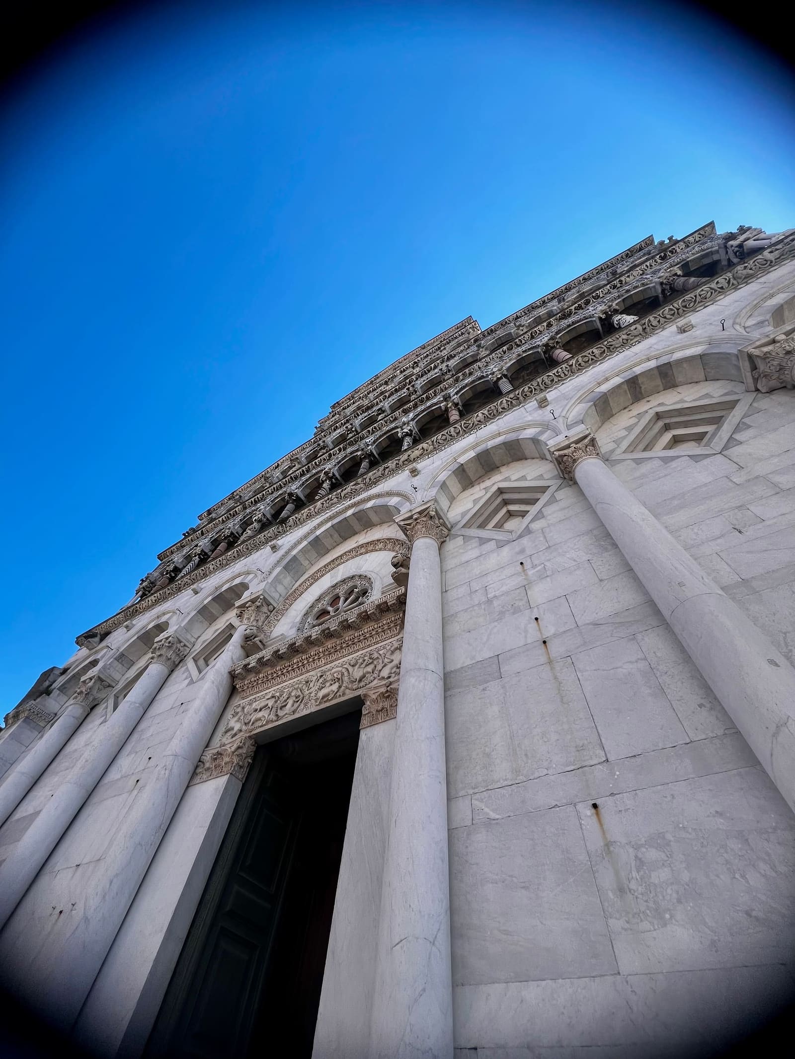 la facciata di marmo bianco di San Michele in Foro, vista dal basso fino alle logge