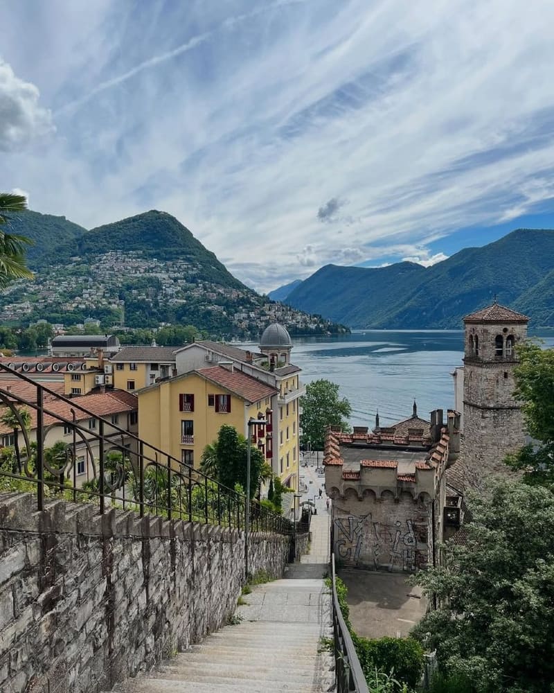 la scalinata che scende verso il lago fra i tetti, con un campanile in pietra e il golfo sullo sfondo