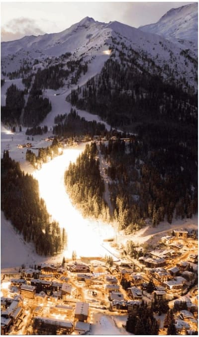 Madonna di Campiglio di notte vista dall'alto, con la pista illuminata che scende fino alle case