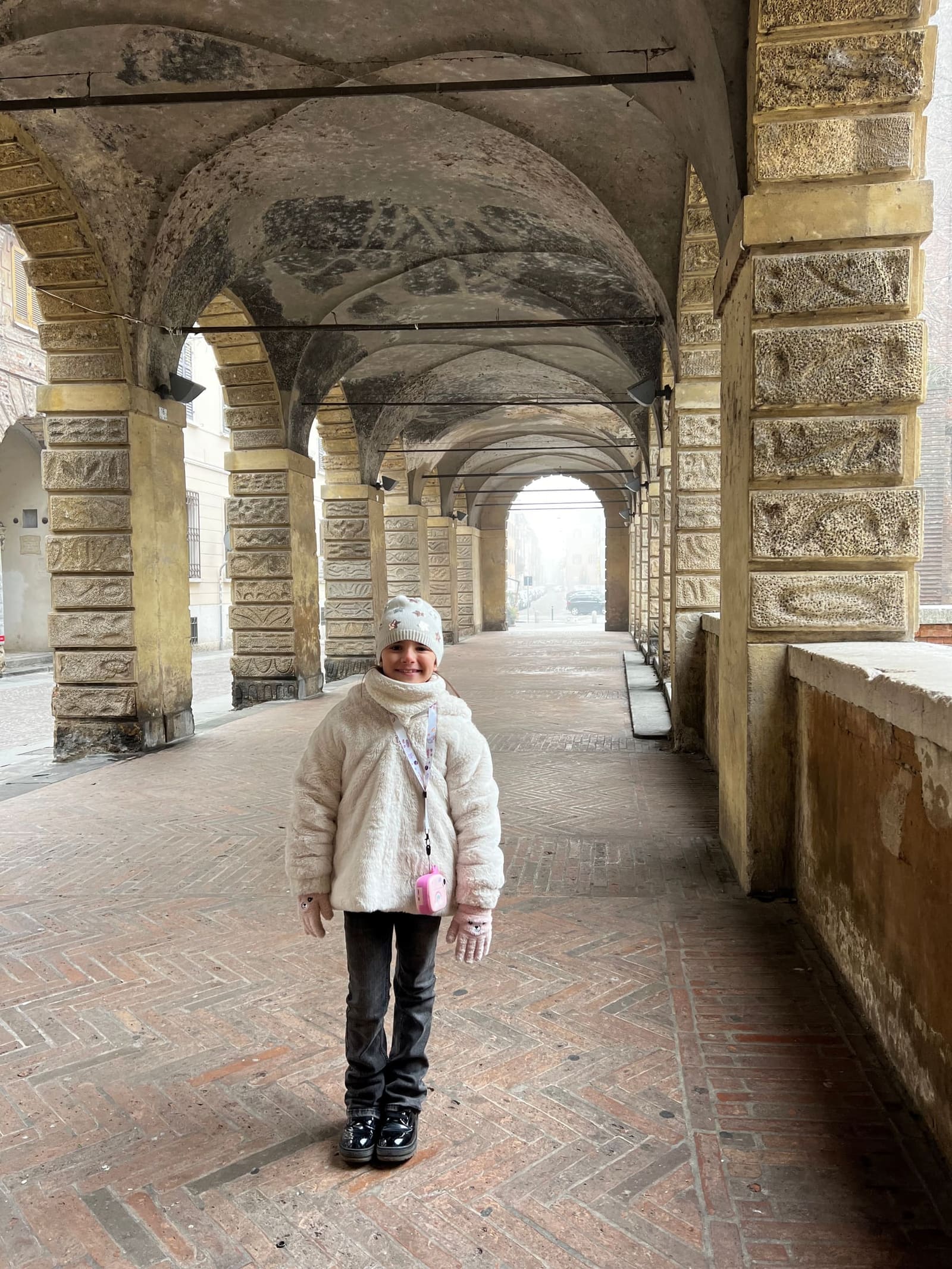 nostra figlia sotto il portico delle Pescherie di Giulio Romano, con la nebbia in fondo alla via