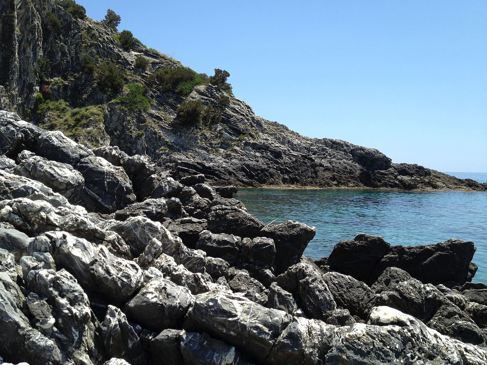 gli scogli grigi della punta e un'insenatura d'acqua calma