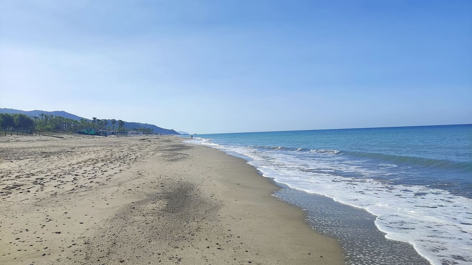la spiaggia vuota, con le onde e la costa in fondo