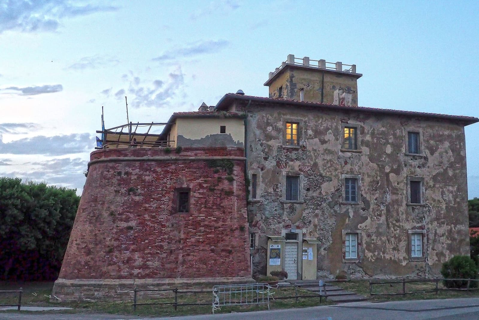 il Forte di Marina di Bibbona nell'ultima luce della sera, con il bastione a scarpa di mattoni, le finestre accese e la torretta di osservazione in cima