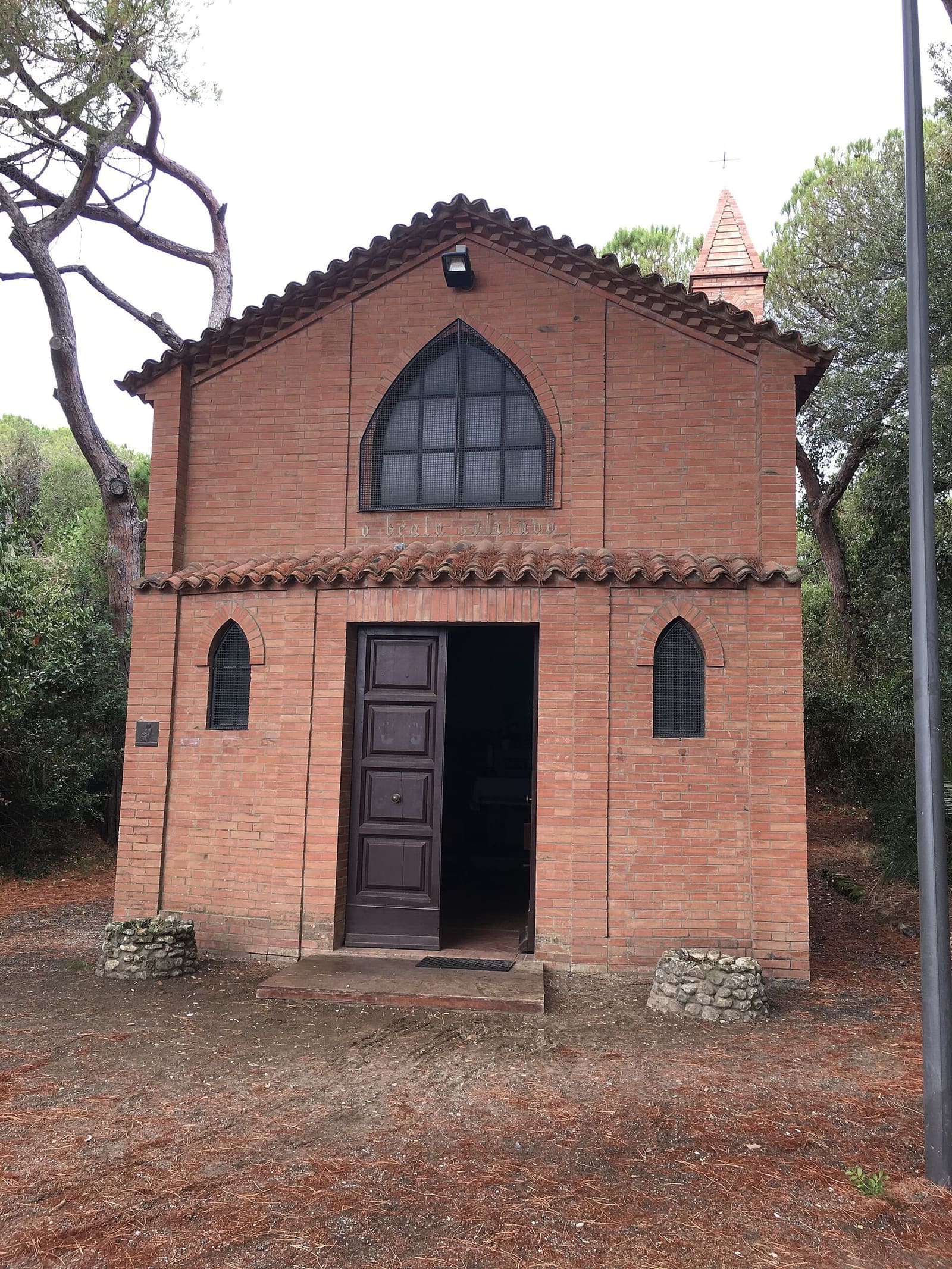 la facciata di mattoni della chiesa fra i pini, con il motto O beata solitudo sotto il finestrone