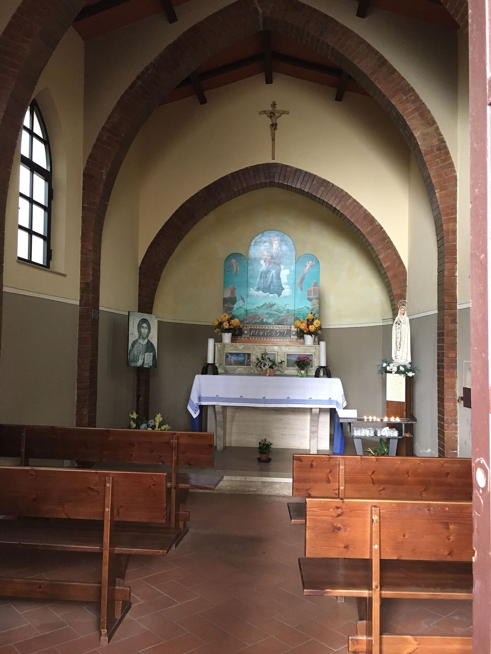 la navata con le panche di legno e gli archi di mattoni fino all'altare