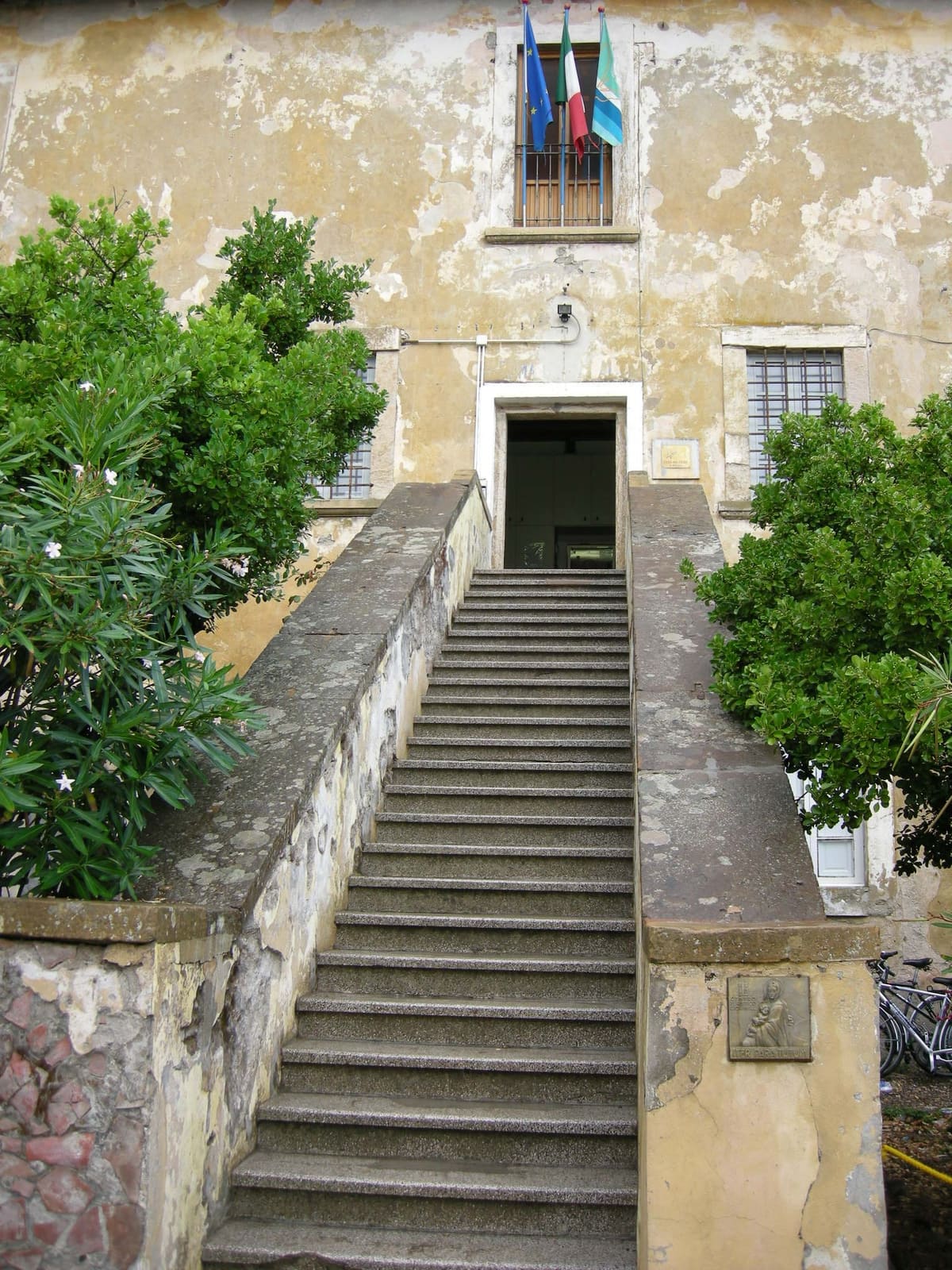 la scala di pietra che sale all'ingresso del Forte fra i cespugli, sotto le bandiere alla finestra