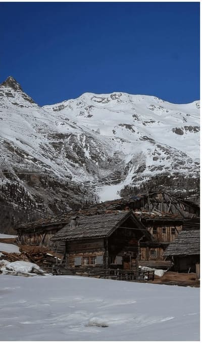 vecchie baite di legno con il tetto in scandole, sotto una parete innevata