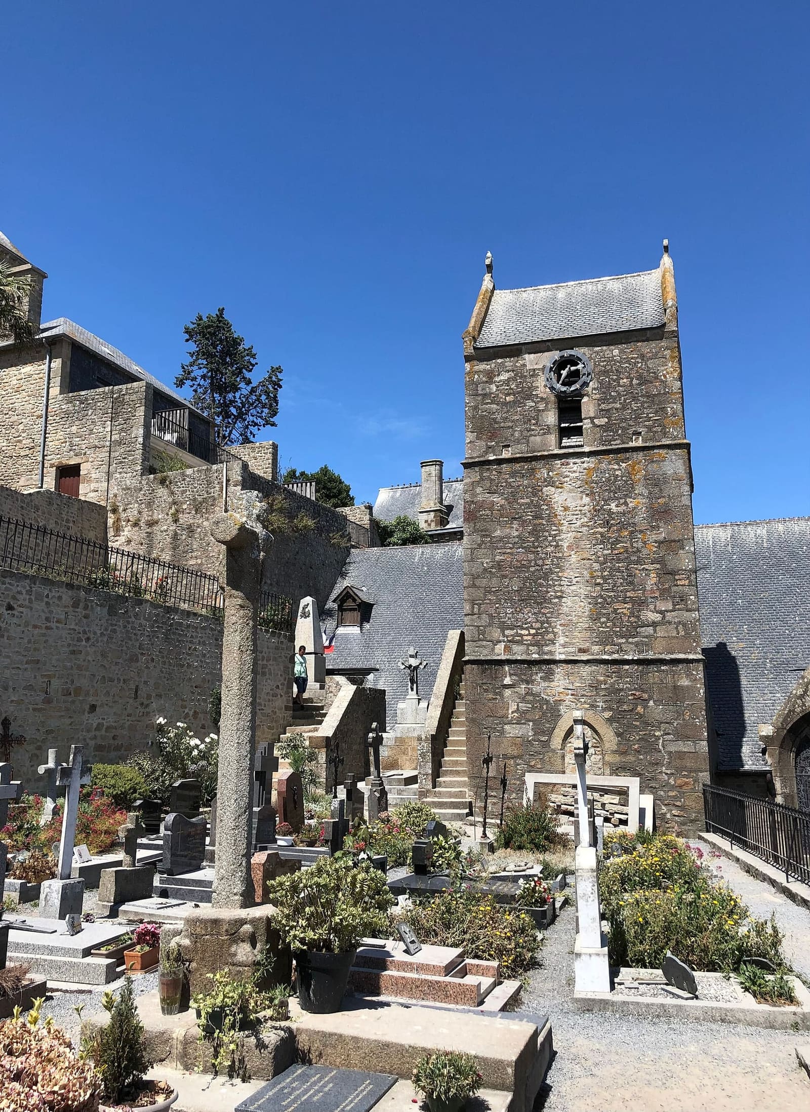 il campanile dell'église Saint-Pierre sopra il piccolo cimitero, con il cielo blu