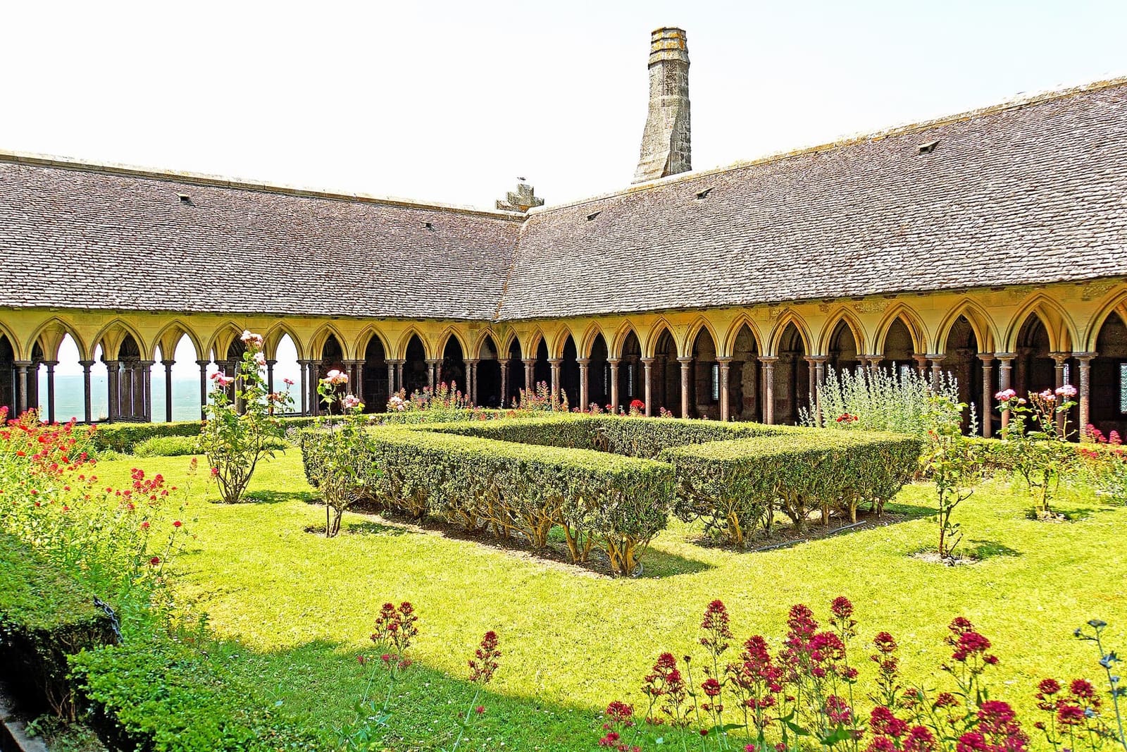 il giardino del chiostro con le siepi e i fiori rossi, fra le colonnine