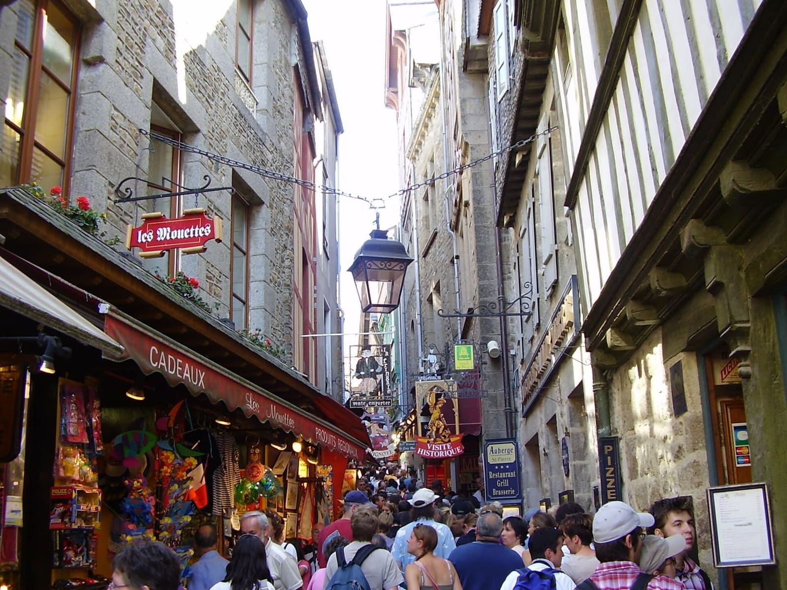 la Grande Rue piena di gente, fra le insegne dei negozi e dei ristoranti