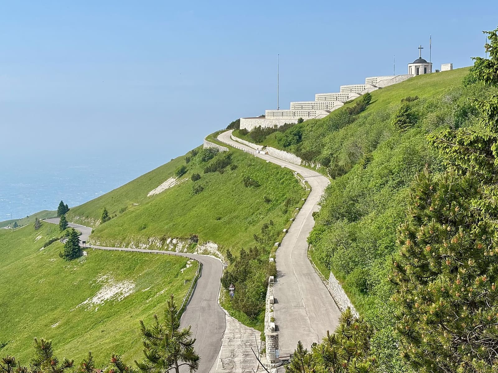 la cima del Grappa con i gironi del Sacrario e la strada che sale fra i prati, in una mattina di giugno
