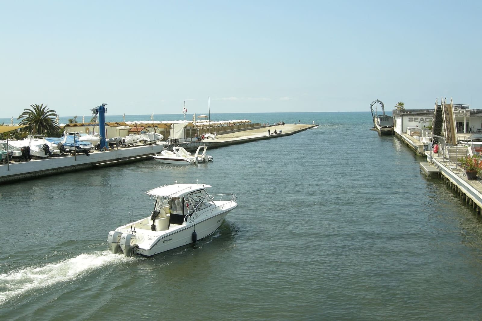 un bateau sort de l'embouchure du Versilia au Cinquale, entre les quais du petit port