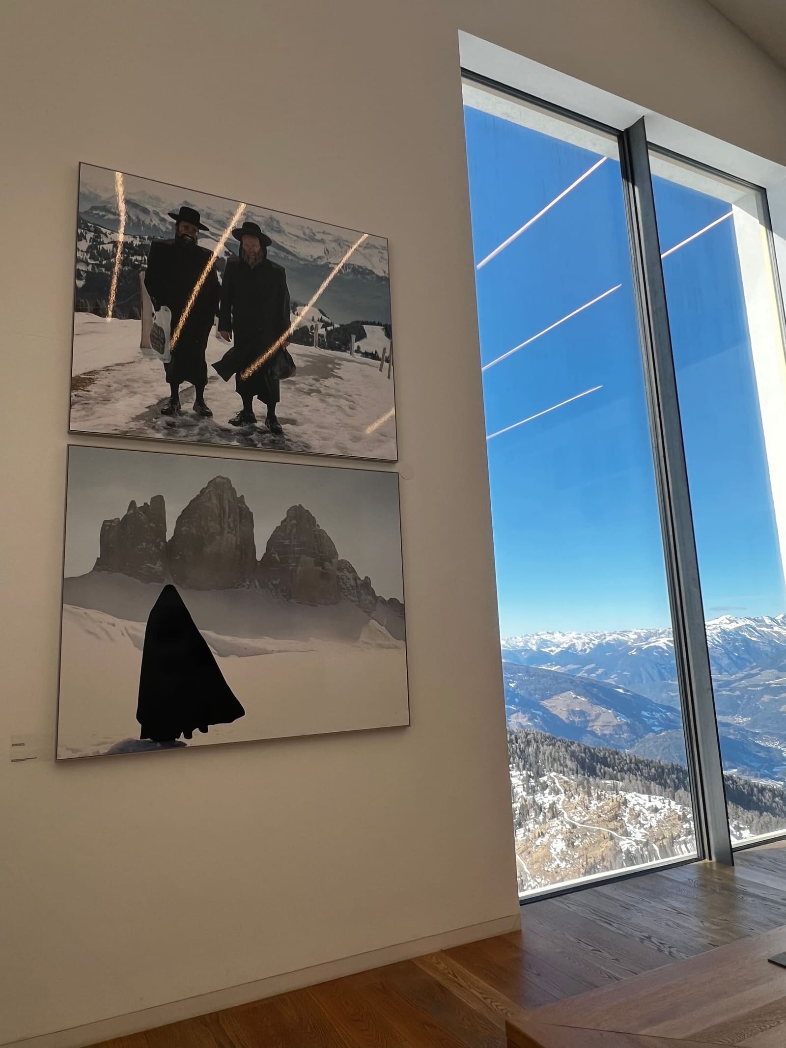 due fotografie appese accanto alla vetrata, e sotto la Val Pusteria innevata
