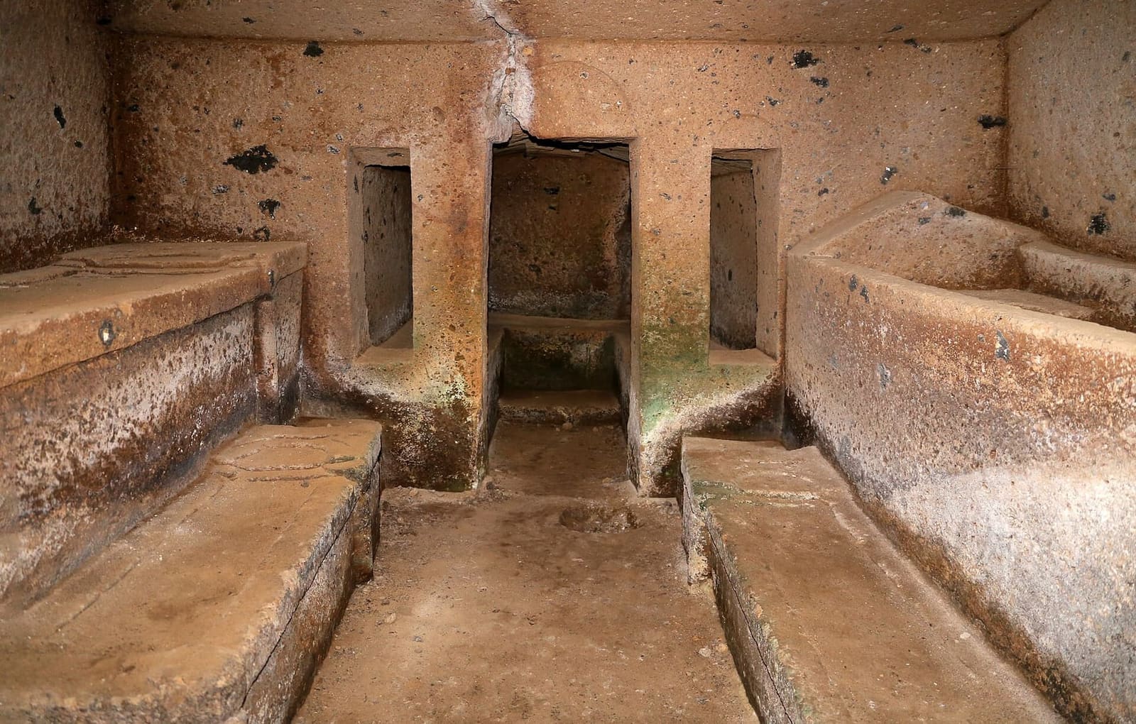 la camera di una tomba della via delle Serpi, con i letti funebri scavati nel tufo ai due lati e in fondo la porta della stanza dopo, fra due finestrelle