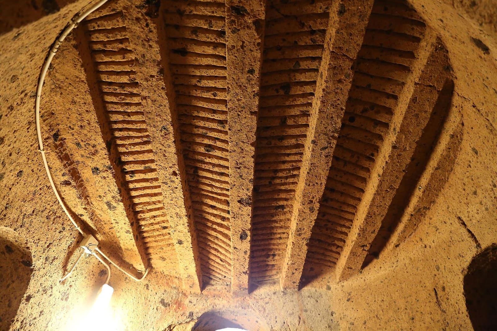il soffitto di una camera del tumulo Maroi, scolpito nel tufo come un tetto di legno: la trave di colmo e i travicelli fitti che scendono ai lati