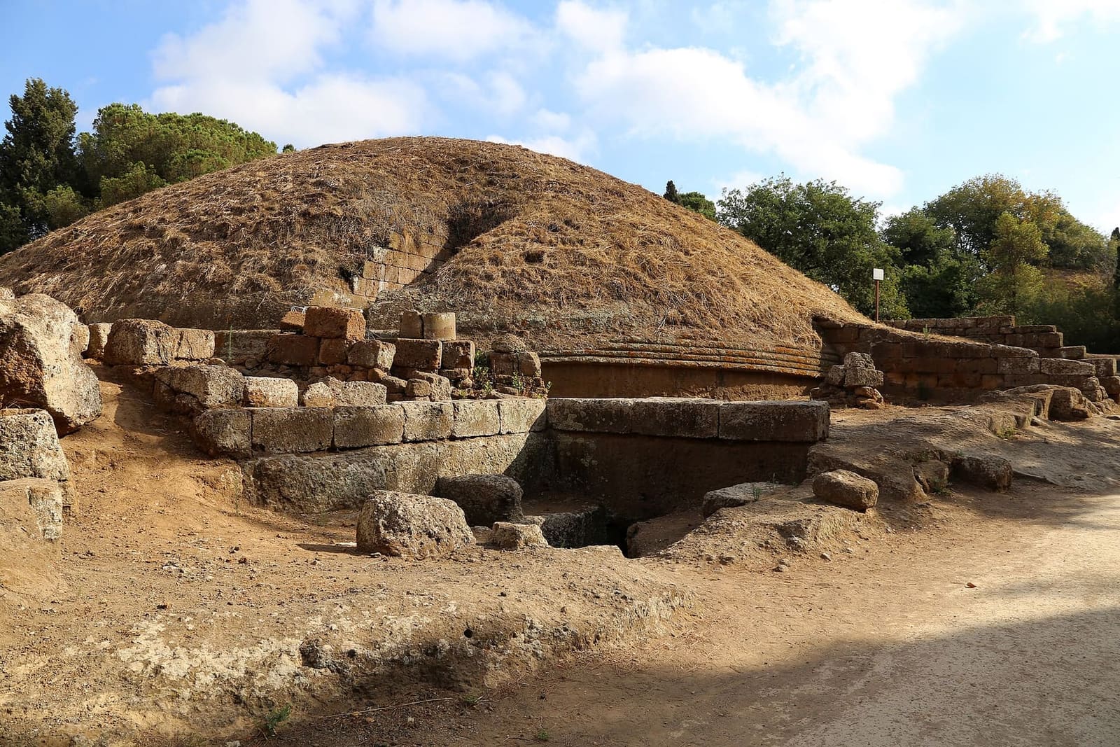 il tumulo II, uno dei grandi: la cupola d'erba secca sopra il tamburo con le modanature, e davanti i blocchi di tufo e l'apertura che scende alle tombe