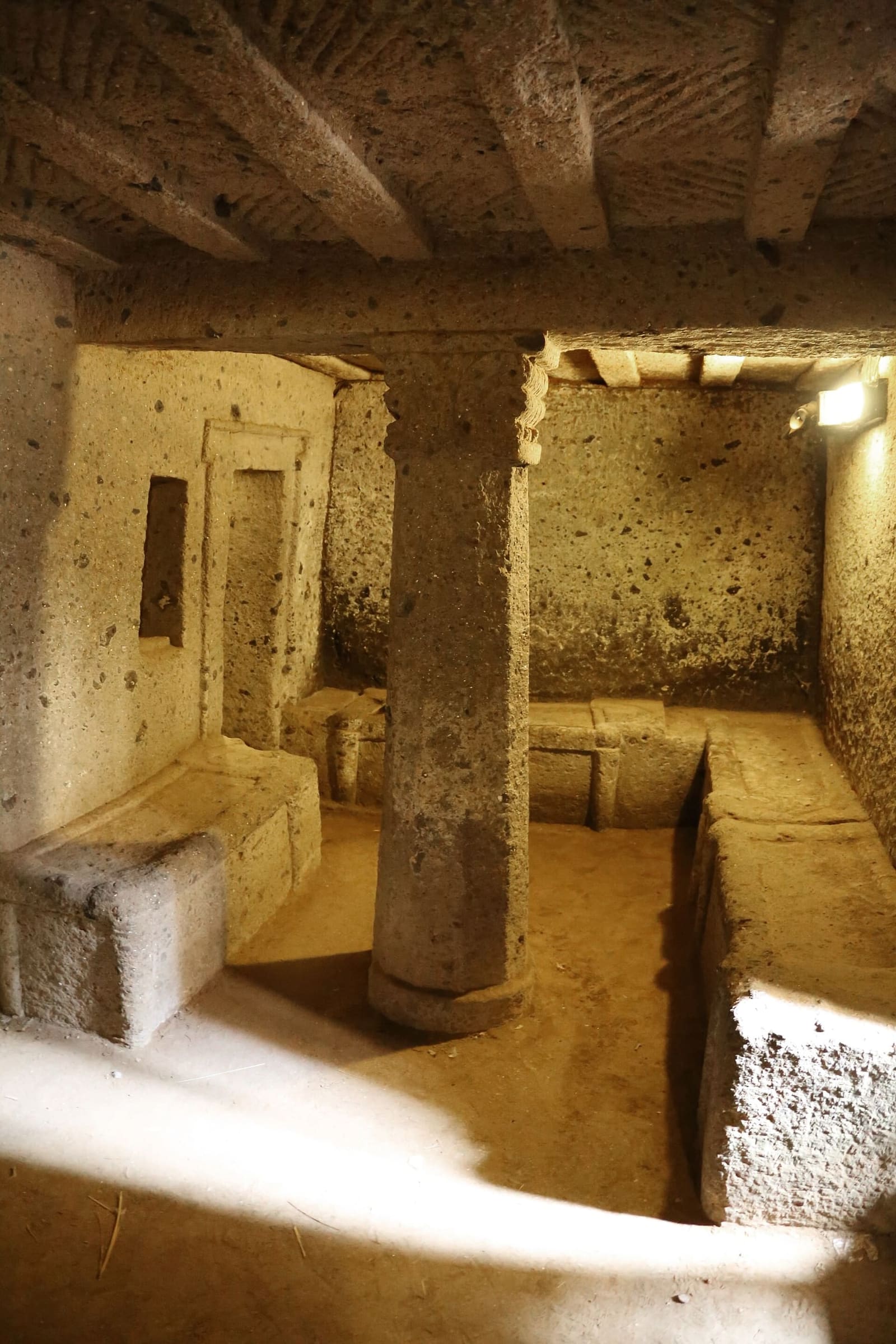 la sala della tomba dei Capitelli, con le colonne dai capitelli a volute, il soffitto a finte travi e i letti delle camere che si aprono intorno