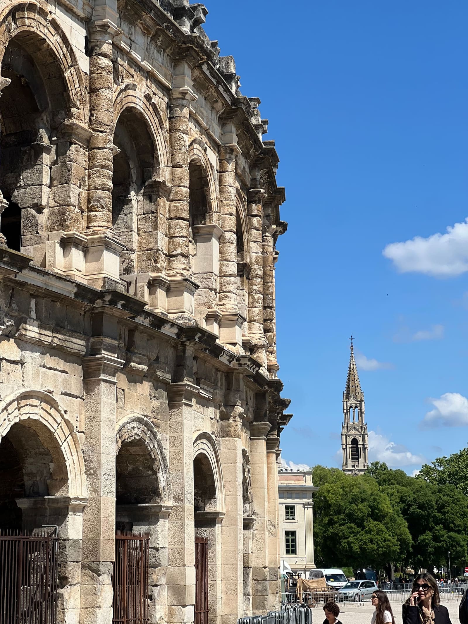 le arcate dell'arena e, dietro, la guglia gotica di una chiesa del centro